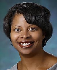 Adrienne Scott, MD Headshot of a smiling woman with dark hair and hoop earrings.